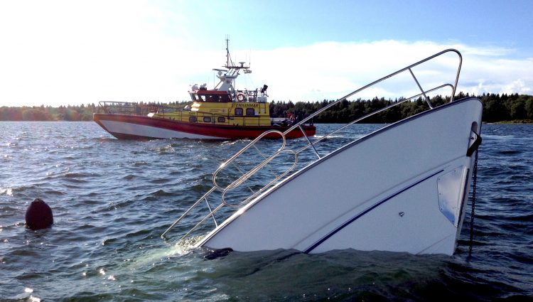 En sjunken båt och en sjöräddningsbåt.